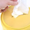 yellow plastic container with a slot cut in it and a homemade cleaning wipe sticking through