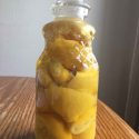 decorative glass jar filled with vinegar and lemon peels on a wooden table