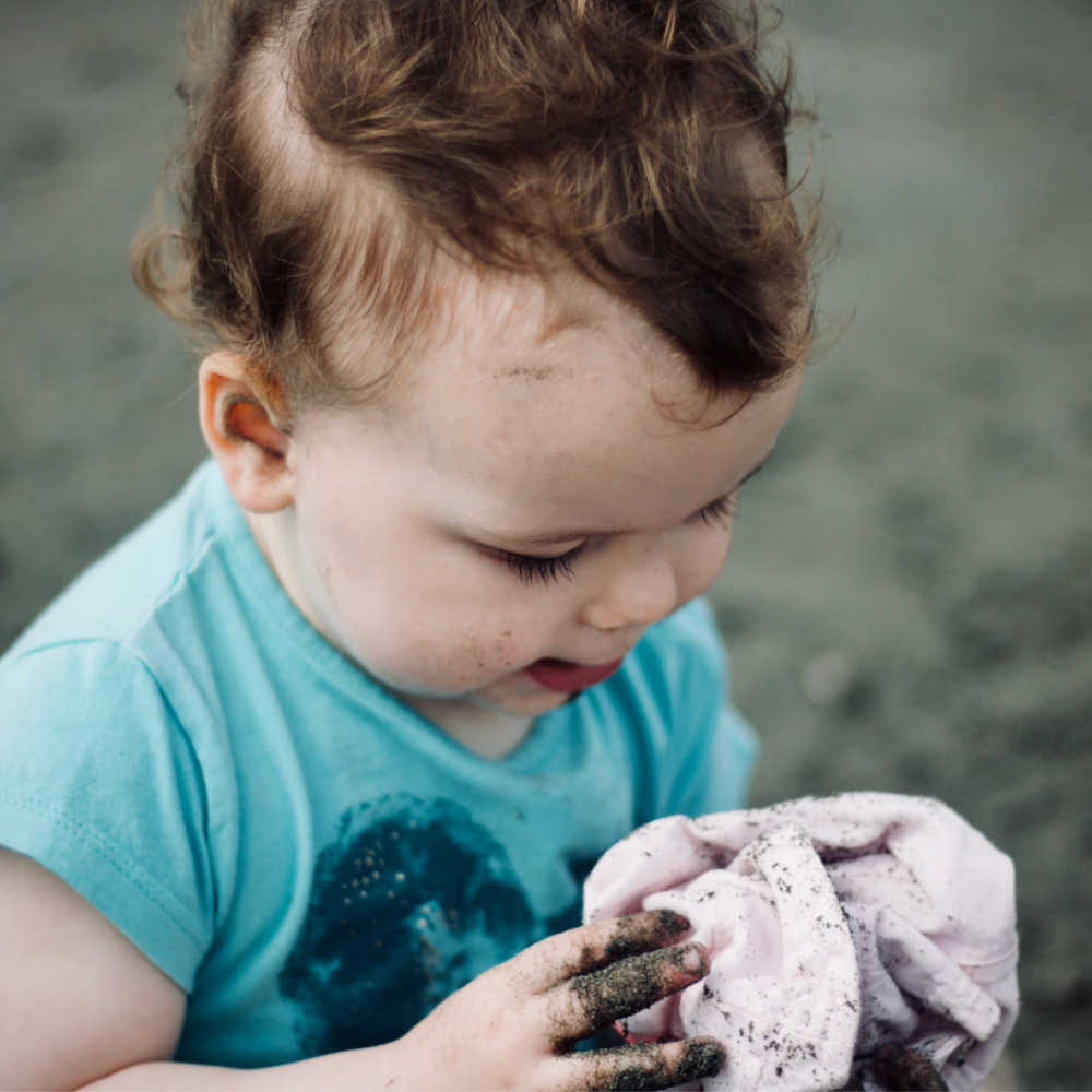 toddler with dirt on hands and clothes
