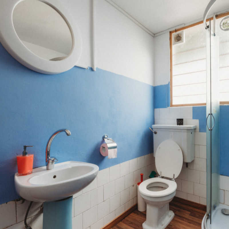 bathroom toilet sink and shower with a blue stripe on the wall
