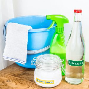 glass jars of baking soda and vinegar with cleaning supplies including a bucket and towel